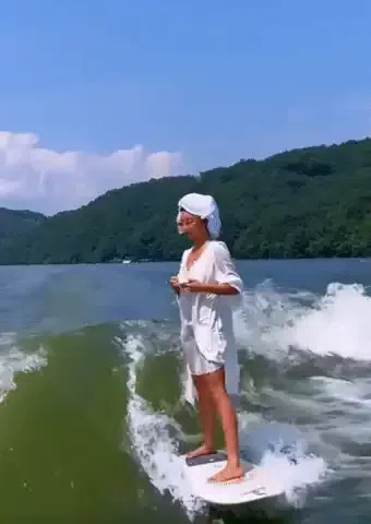A woman drinking her coffee on a surfboard